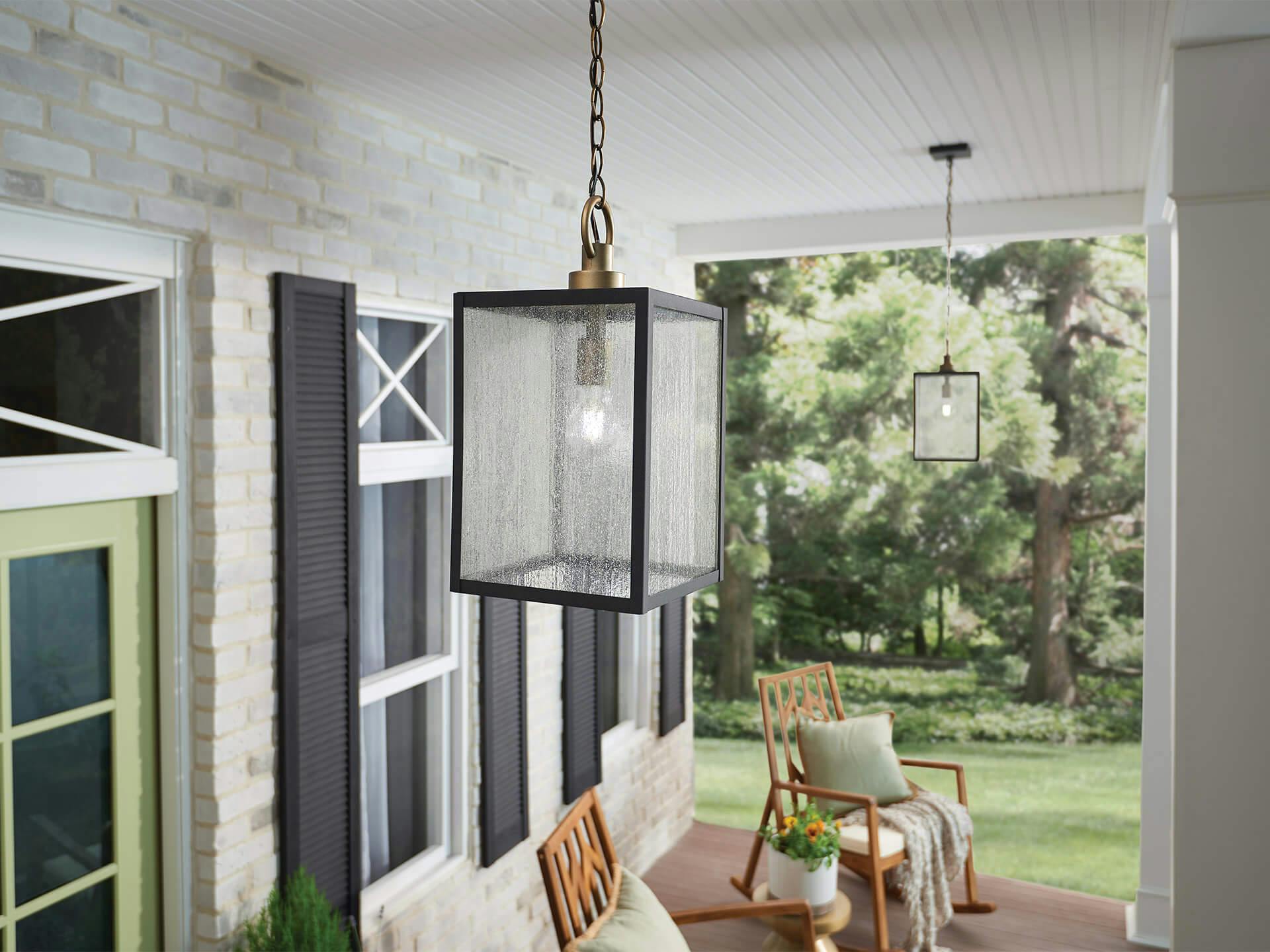 Exterior image of a white brick front porch with rocking chairs lit by Lahden pendants during the day 