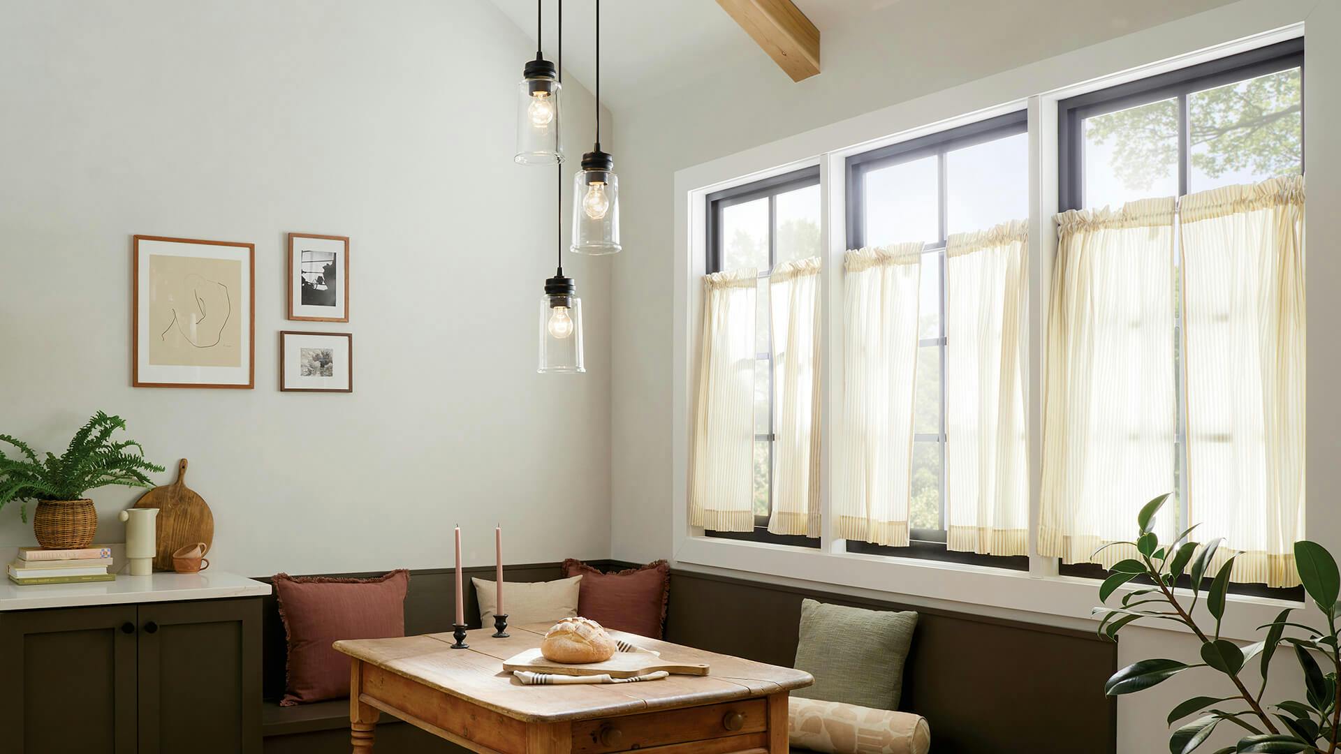 Corner dining nook with three windows pouring in morning light, featuring Jaylen pendant lights in black finish