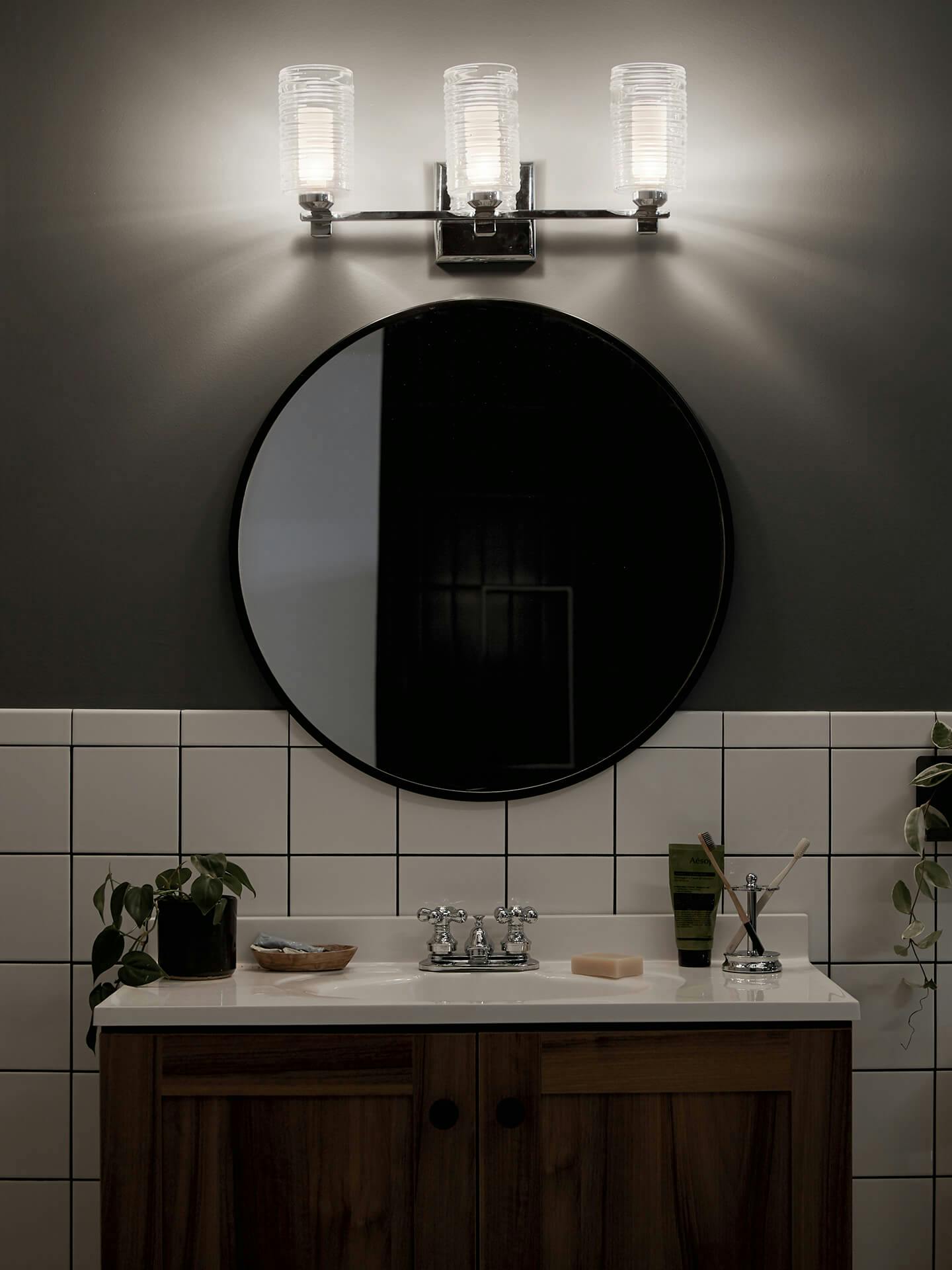 Modern bathroom at night with only Giarosa vanity lights on above a round mirror
