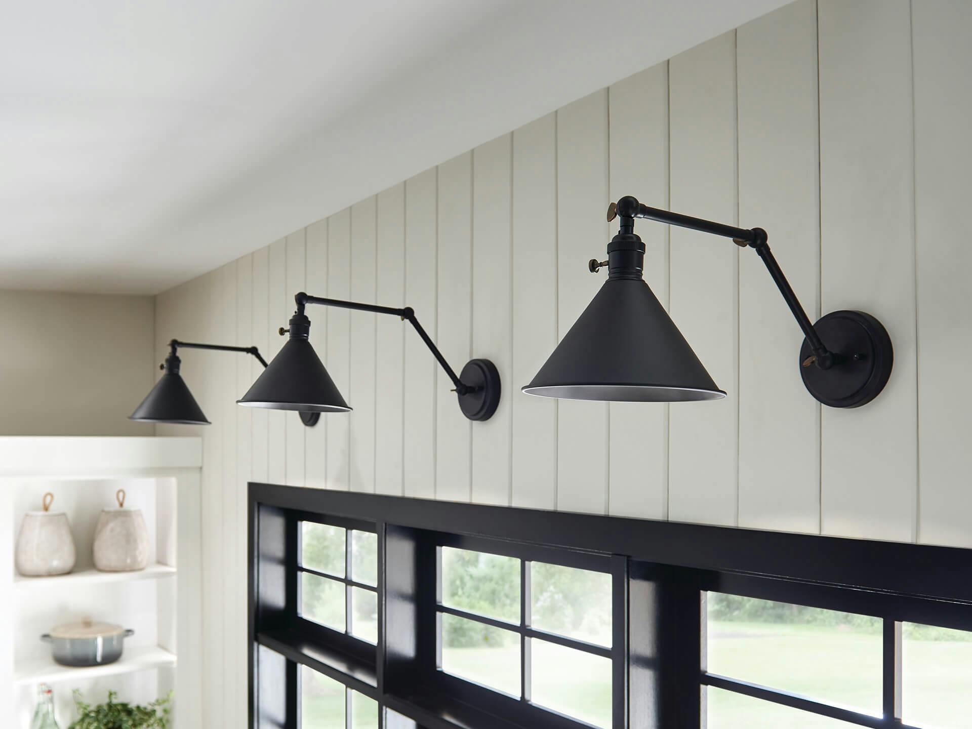 Close up on three ellerbeck sconces in black finish above a kitchen widow