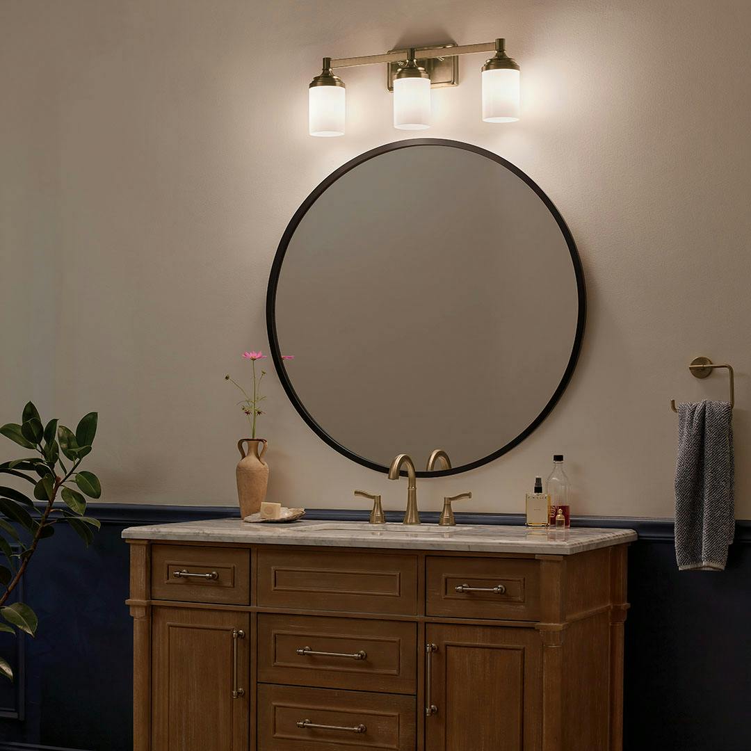 Bathroom at night with the Noha 24 In. 3-Light Champagne Bronze Vanity Light with Opal Glass Shades