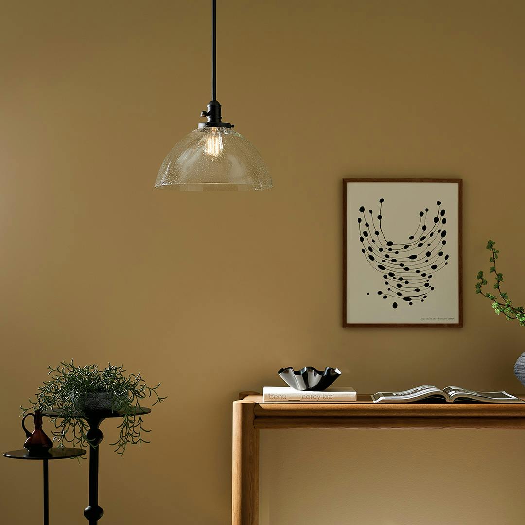 The Avery 11" 1-Light Dome Pendant with Clear Seeded Glass in Black hung by console table