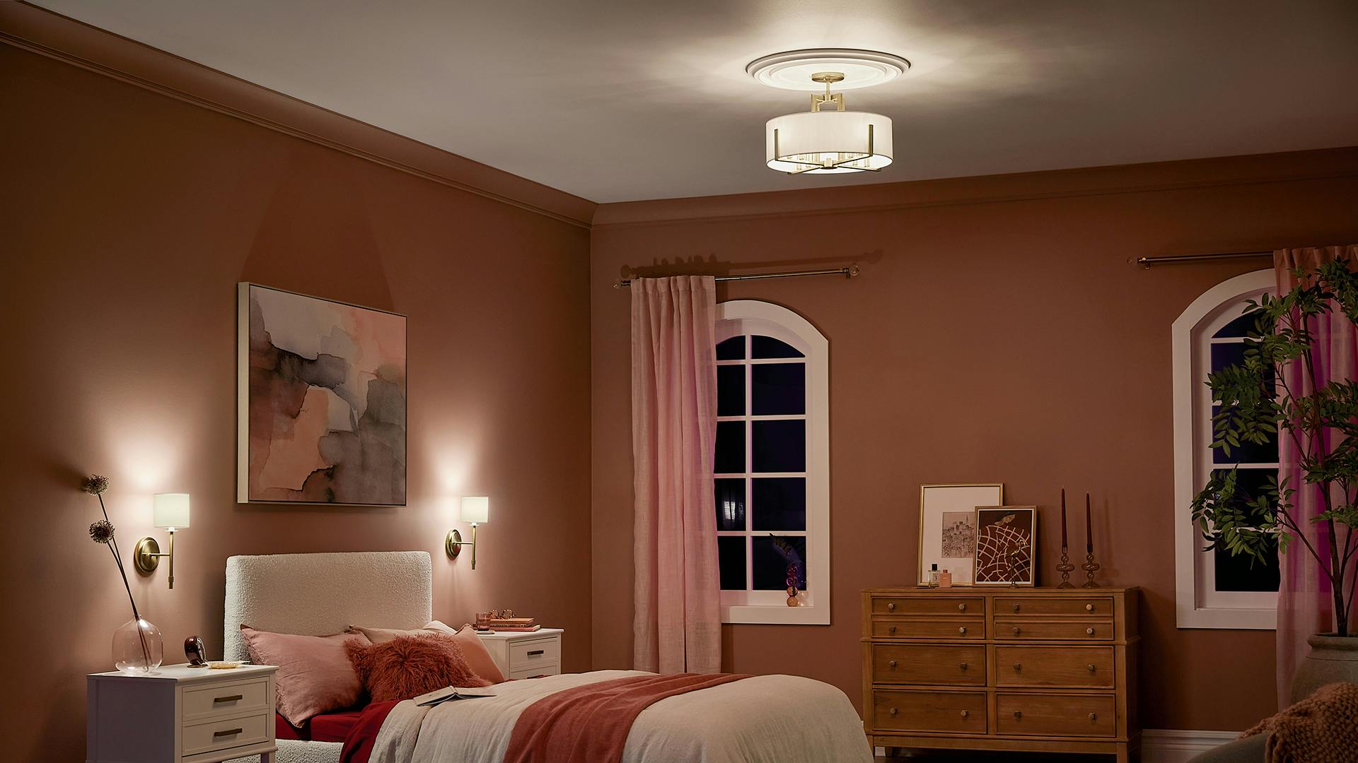 Bedroom at night with Pink accents and Malen Chandelier over the bed and Ali sconces on the side of the bed.