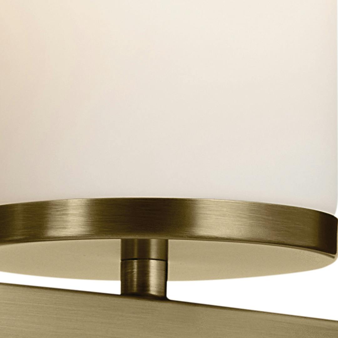 Close up view of the Crosby 23" 3-Light Vanity Light with Satin Etched Cased Opal Glass in Natural Brass on a white background