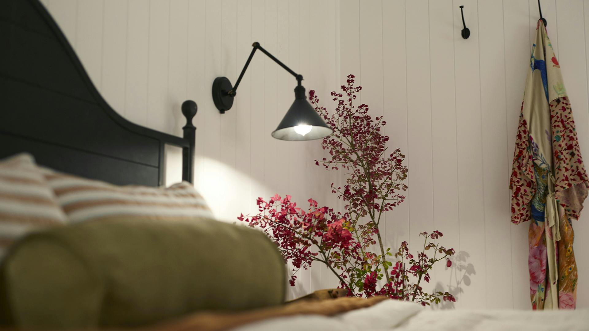 Close-up of Ellerbeck wall sconce lighting up nightstand 