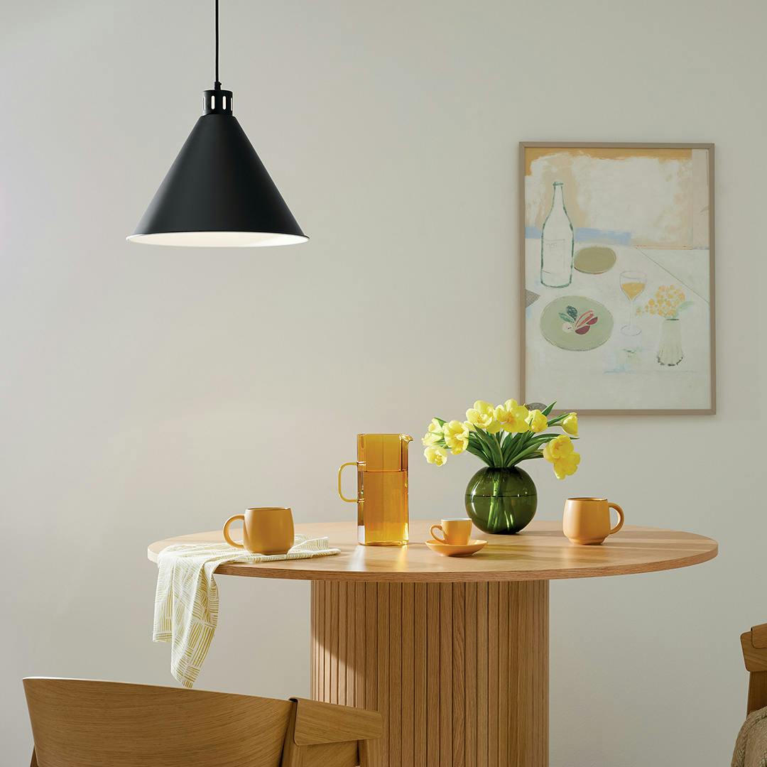 The Zailey 14.25" 1-Light Cone Pendant in Black hung in front of furniture and wall