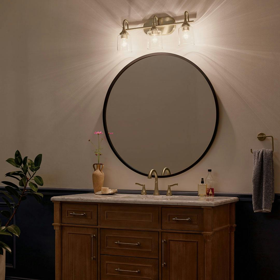 Bathroom at night with the Erta 24 In. 3-Light Champagne Bronze Vanity Light with Clear Glass Shades
