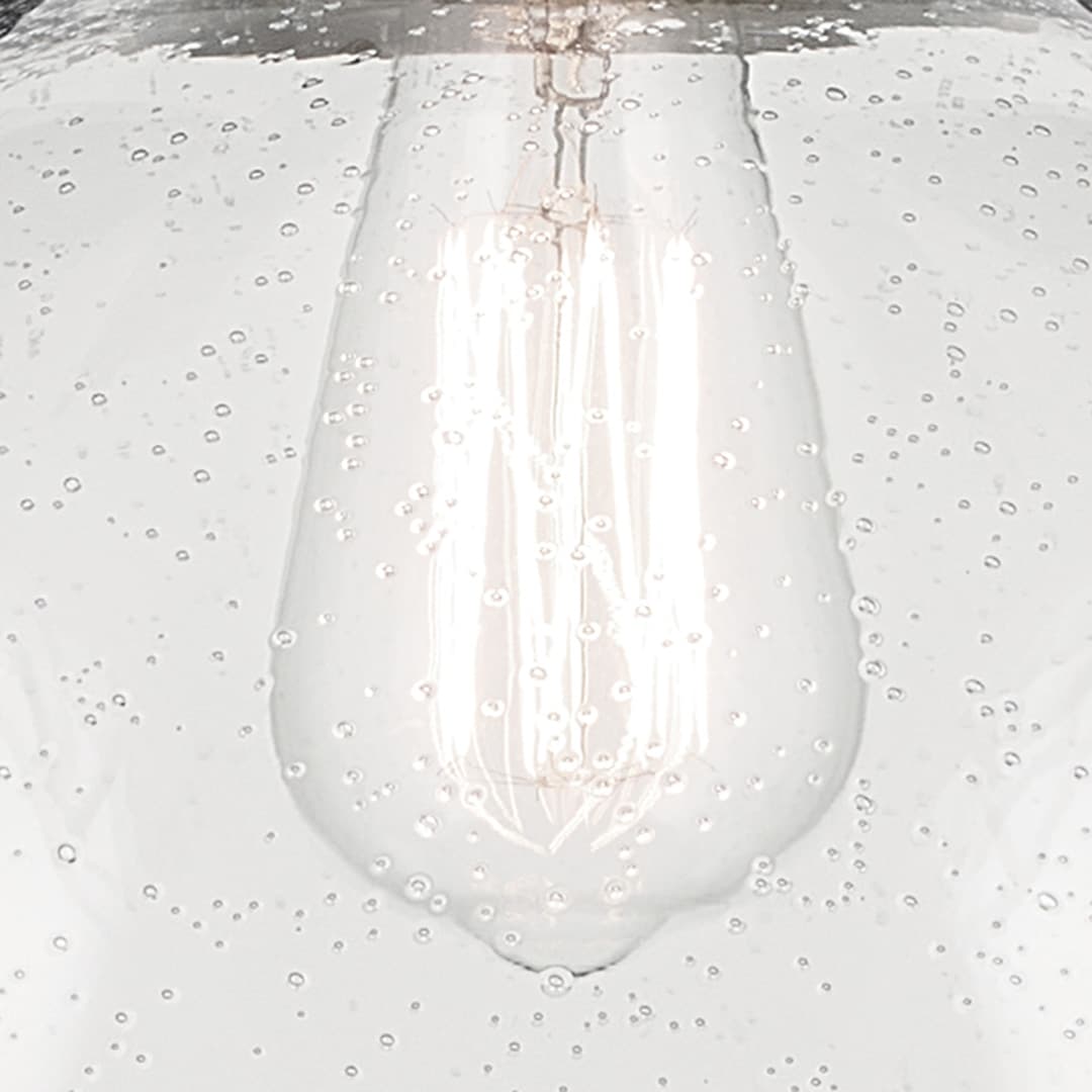 Close up view of the Avery 11" 1-Light Dome Pendant with Clear Seeded Glass in Natural Brass on a white background