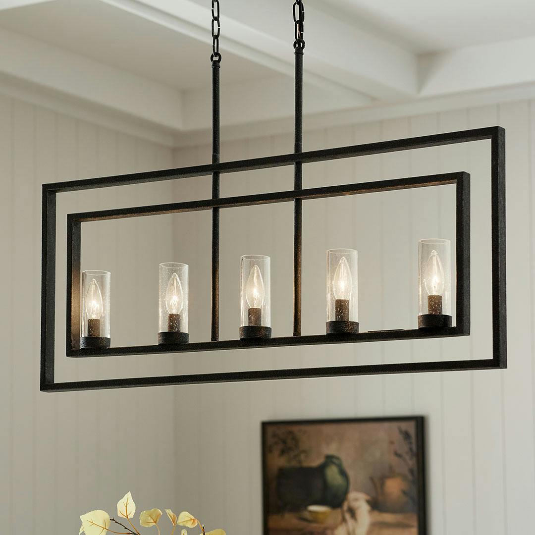 Dining room in day light with the Vervain 5 Light Linear Chandelier in Distressed Black
