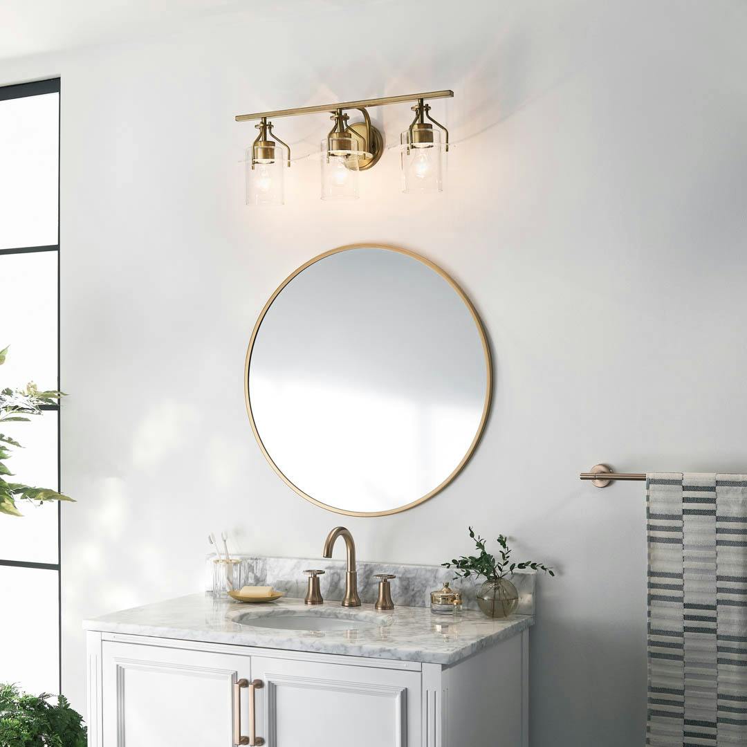 Day time bathroom with Everett 24 Inch 3 Light Vanity Light with Clear Glass in Natural Brass