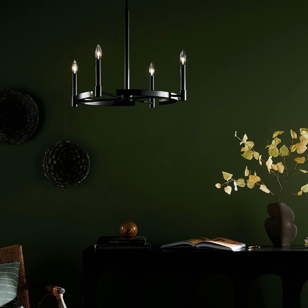 The Tolani 20.25" 4-Light Chandelier in Black hung in front of furniture and wall