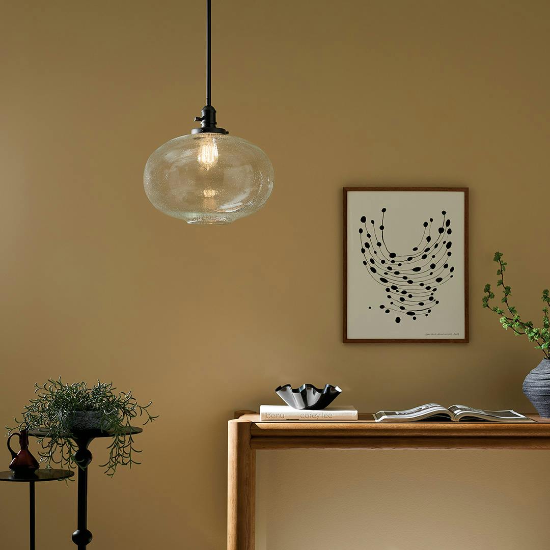 The Avery 14" 1-Light  Globe Pendant with Clear Seeded Glass in Black hung by console table