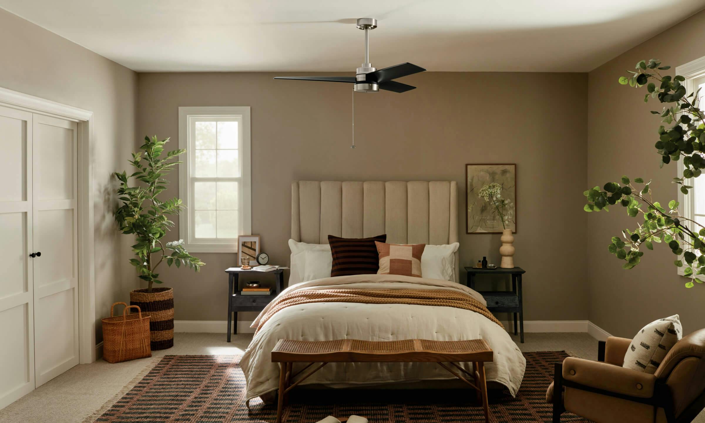 A bedroom with a Spyn fan above the bed during the day 