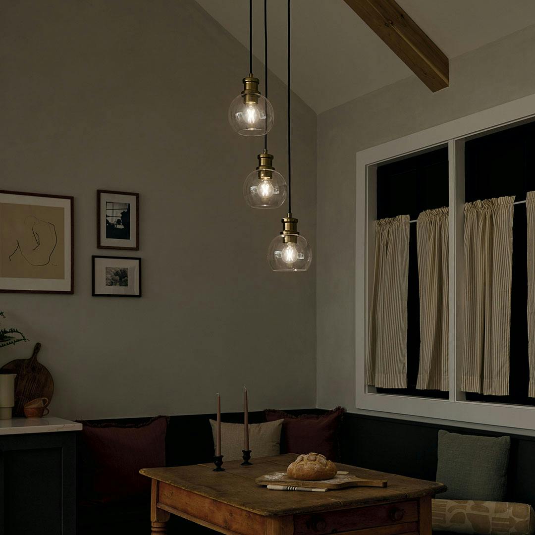Dining room at night with the Clove 3 Light Cluster Pendant in Black and Brushed Natural Brass